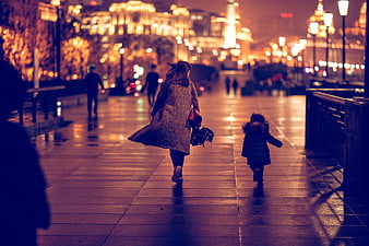 Mother and Child Running on Wet City Street at Night