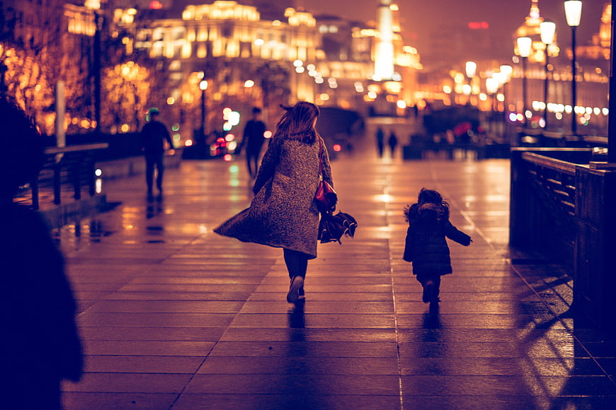 Mother and Child Running on Wet City Street at Night