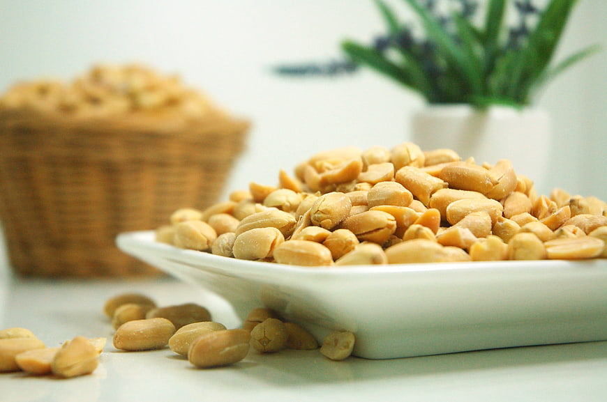 Roasted peanuts in white bowl with basket background