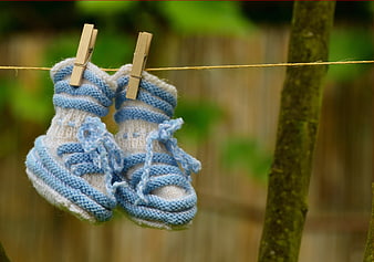 Hand-knitted blue and white baby booties hanging on a clothesline