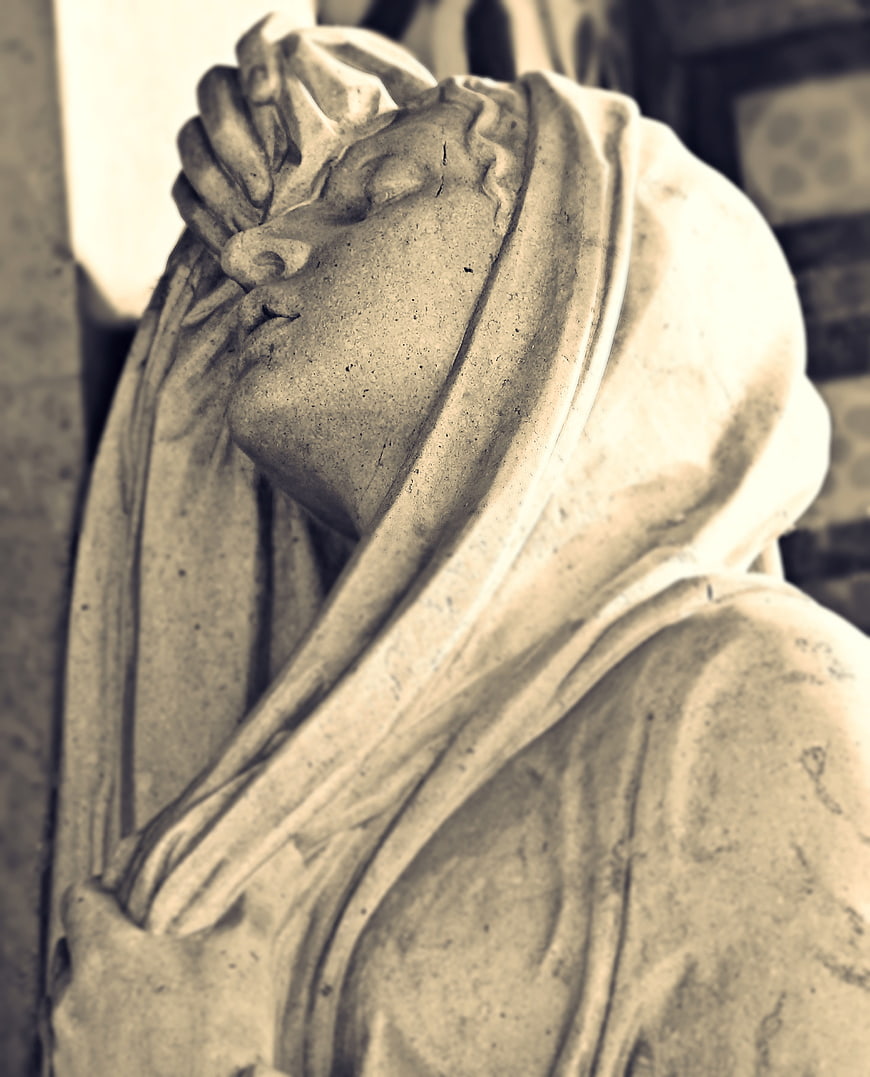 Close-up of a weeping stone angel statue in a cemetery