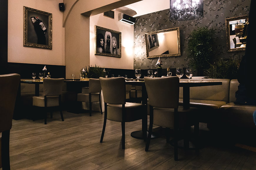 Dimly lit restaurant interior with tables and framed art