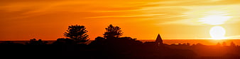 Panoramic sunset silhouette of trees and church spire