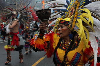 Indigenous Woman in Traditional Feather Headdress Holding Ritual Vessel