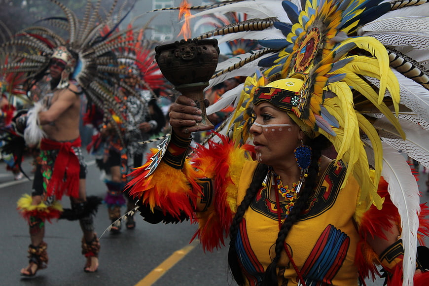 Indigenous Woman in Traditional Feather Headdress Holding Ritual Vessel