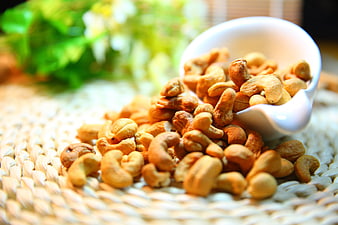 Roasted Cashew Nuts Spilling from White Bowl on Woven Mat