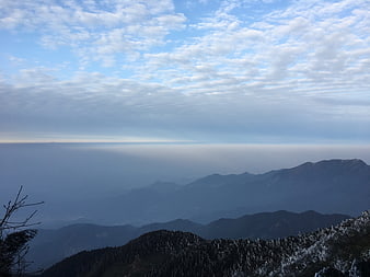 Snowy mountain peaks with layered blue ridges and cloudy sky
