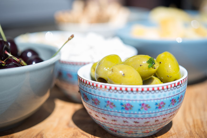 Green olives in a patterned bowl on a wooden table