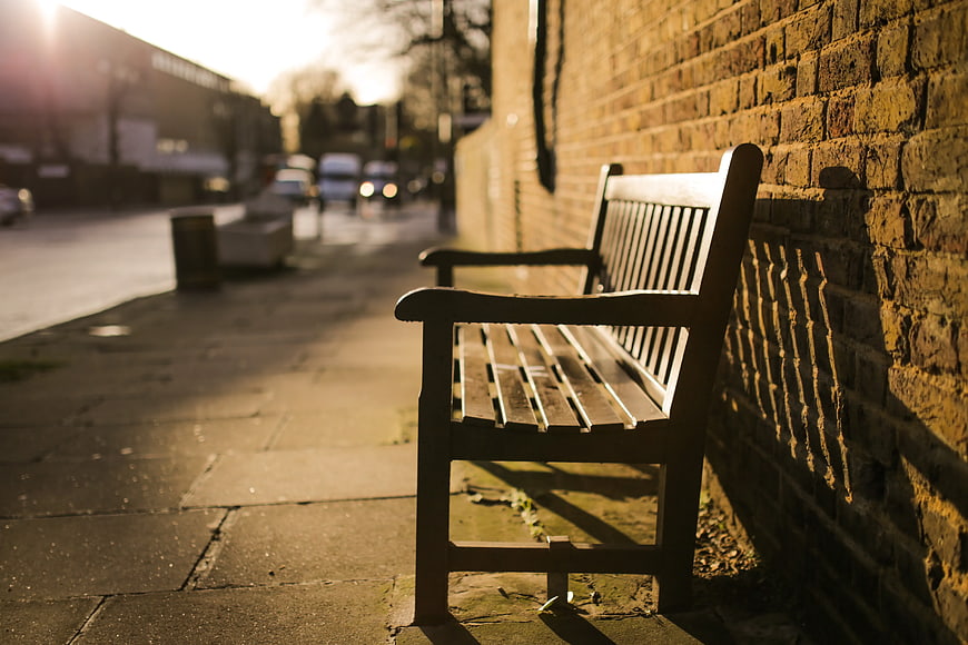 Empty Wooden Bench Against Brick Wall in Golden Hour Sunlight