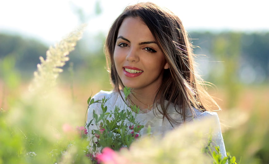 Smiling Woman in White Shirt in Sunny Flower Field