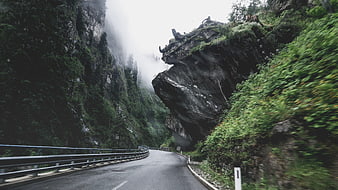 Winding mountain road through misty forest cliffs
