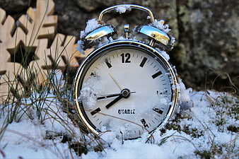 Vintage Alarm Clock Covered In Snow On Winter Grass