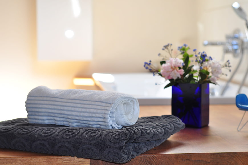 Rolled towels and flowers on wooden bathroom counter