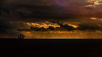 Silhouette of Sailing Ship on Dark Ocean at Sunset