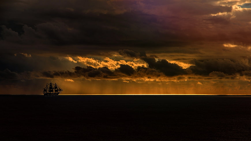 Silhouette of Sailing Ship on Dark Ocean at Sunset
