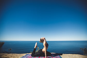 Woman doing yoga on cliff overlooking ocean
