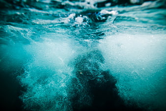 Underwater view of turbulent blue water with bubbles and foam