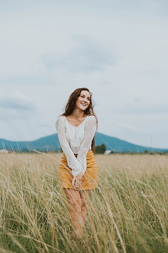 Happy Woman Smiling in Tall Grass Field with Mountains