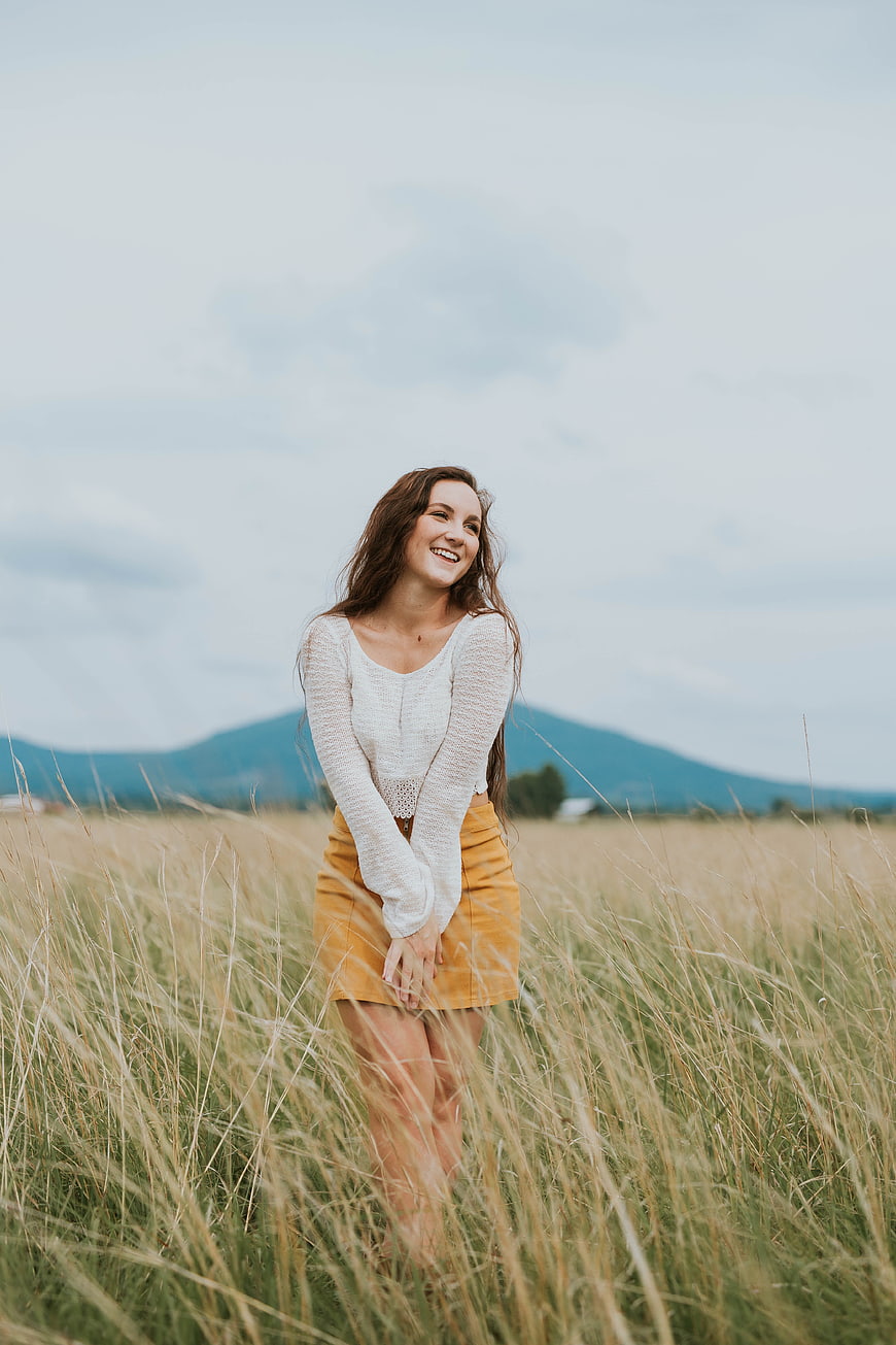 Happy Woman Smiling in Tall Grass Field with Mountains