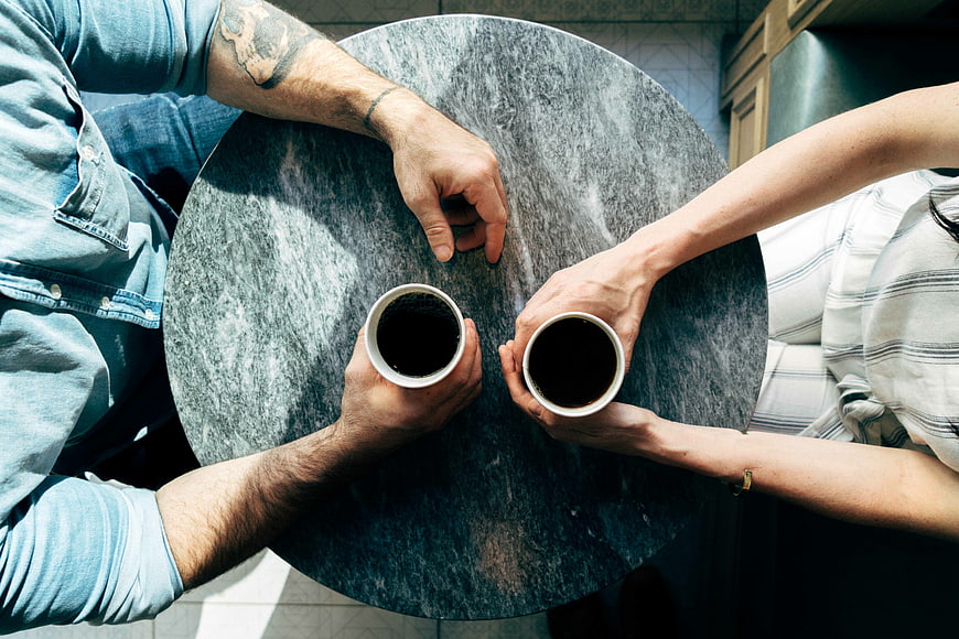 Top view of couple holding coffee cups on table