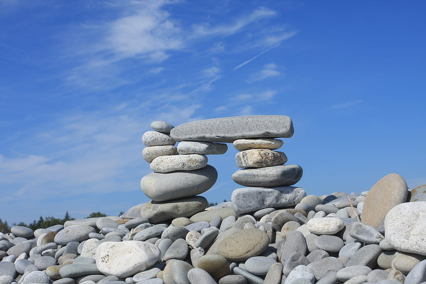 Balanced Stone Arch on Beach Against Blue Sky