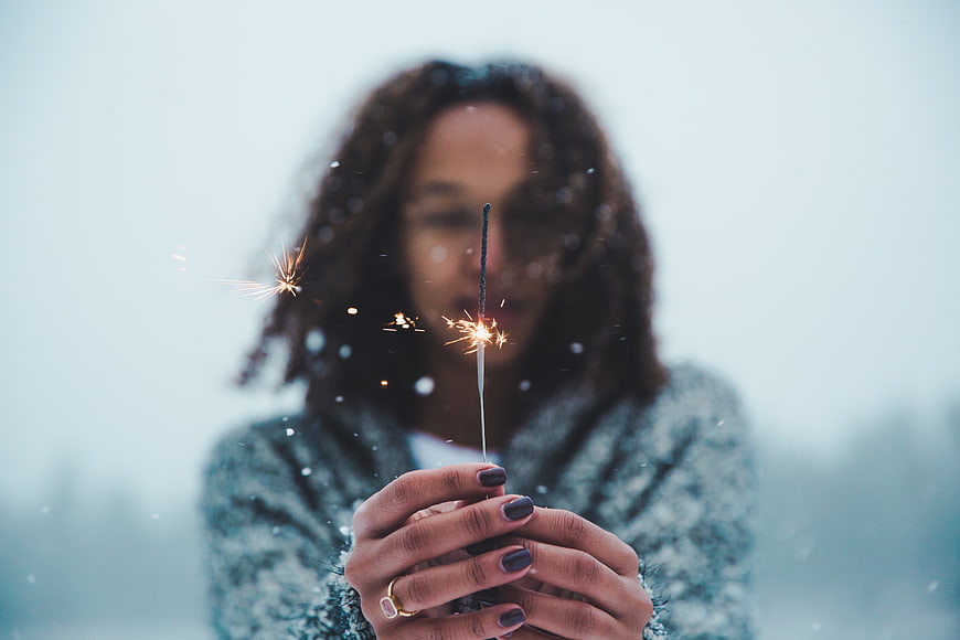 Woman holding sparkler in winter snow