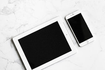 White tablet and smartphone on white marble background