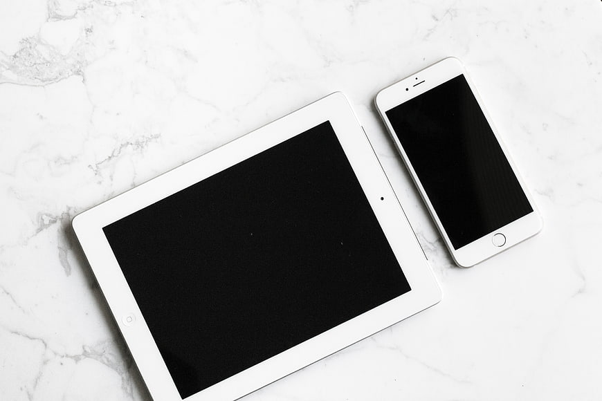 White tablet and smartphone on white marble background