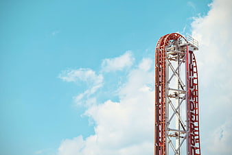 Red Roller Coaster Track Against Blue Sky with Clouds