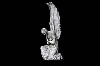 Kneeling stone angel statue with wings on black background