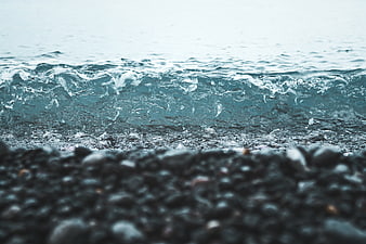 Close-up of ocean waves crashing on a pebble beach