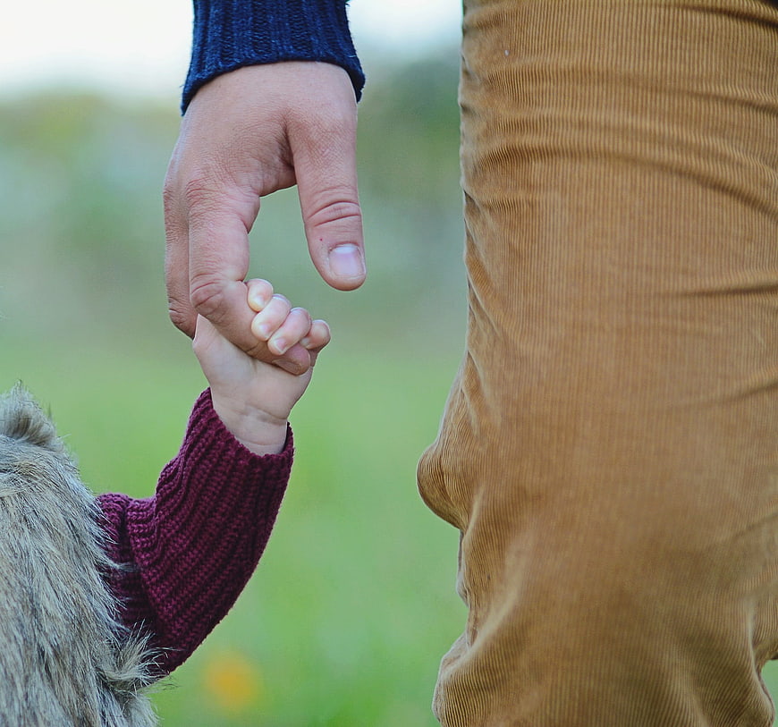 Father and daughter holding hands in a park