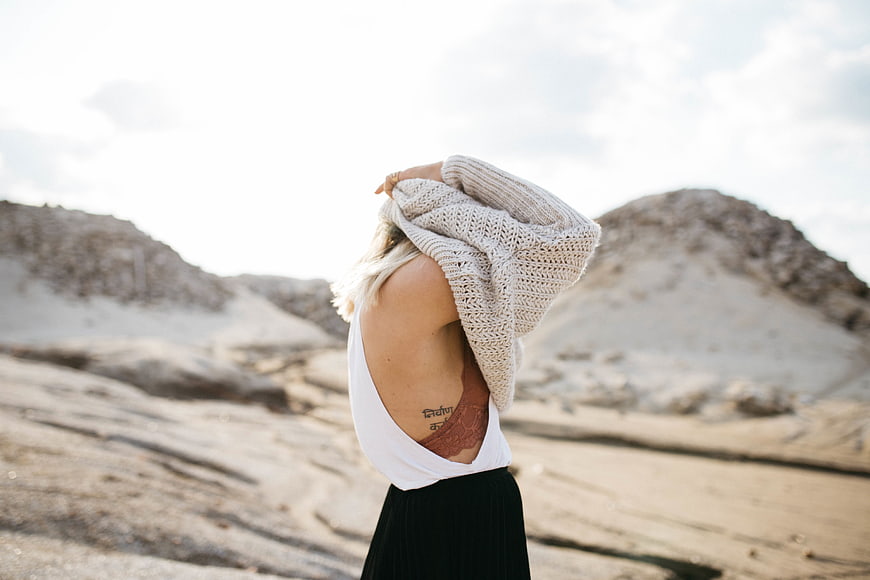 Woman in Desert Landscape Pulling Sweater Over Head
