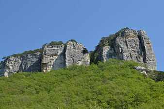 Limestone cliffs with green forest and blue sky