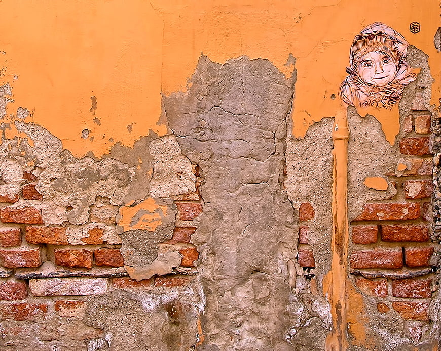 Street art mural of a child on weathered orange brick wall