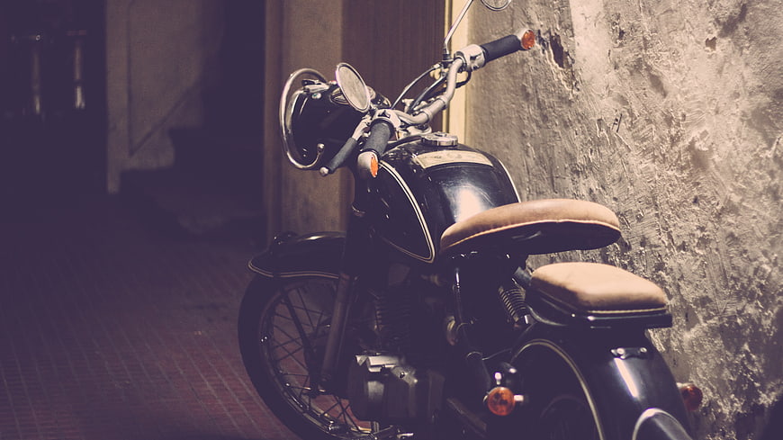 Vintage Black Motorcycle Parked Against Textured Wall