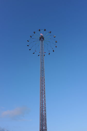 Tall swing ride tower against clear blue sky