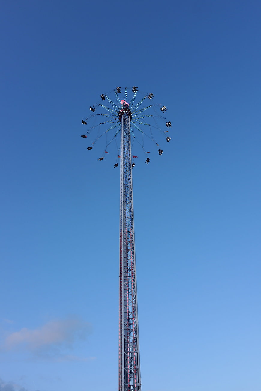 Tall swing ride tower against clear blue sky