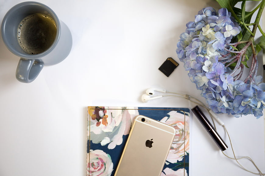 Flat Lay Workspace with Coffee, Flowers, and Smartphone