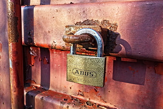 Rusty padlock on weathered metal gate