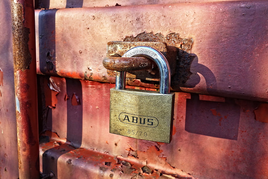 Rusty padlock on weathered metal gate