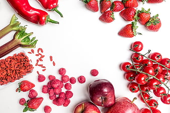 Flat lay of red fruits and vegetables on white background