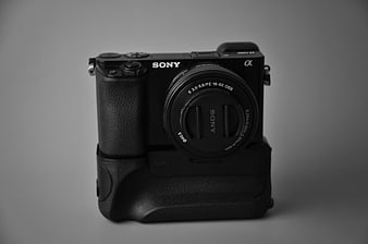 Black Sony Alpha Camera with Battery Grip on Gray Background
