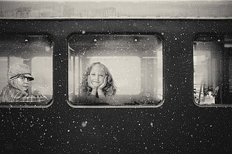 Children and cat looking out of train windows in snow