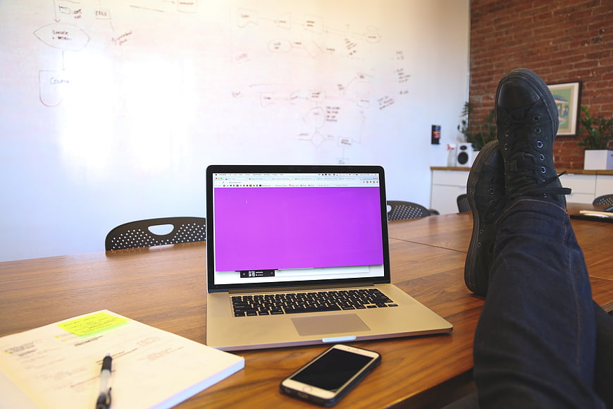 Relaxed freelancer with feet on desk and laptop in modern office