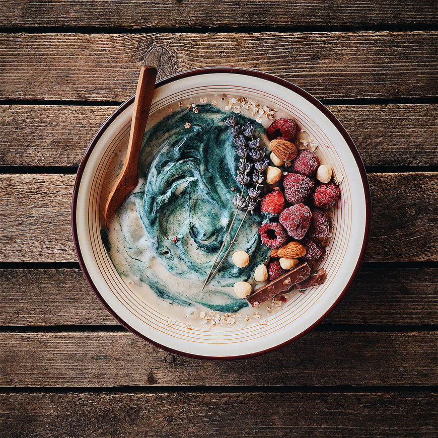 Top view of blue spirulina smoothie bowl with raspberries and nuts