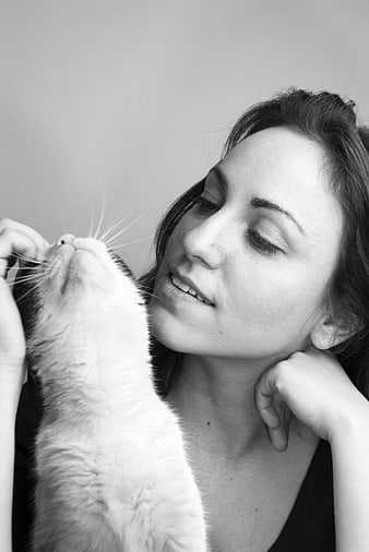 Black and white portrait of a woman smiling at a cat
