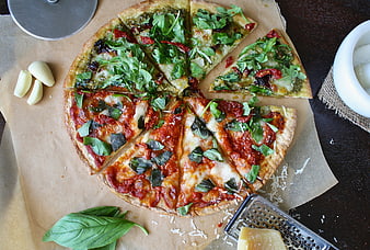 Top view of sliced homemade pizza with pesto and tomato toppings