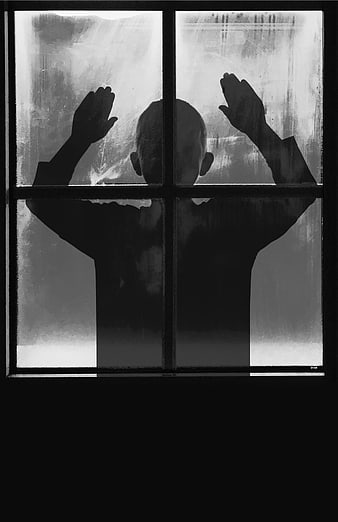 Silhouette of child pressing hands against frosted window