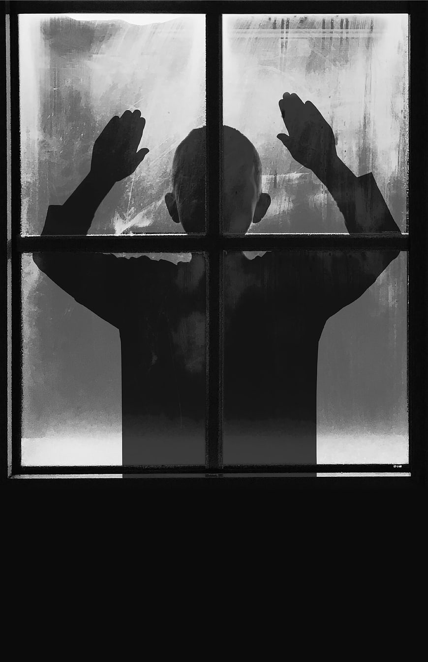 Silhouette of child pressing hands against frosted window